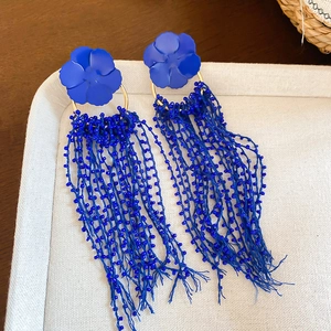 Detailed view of blue matte flower earrings with long beaded fringe tassels and gold rings