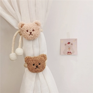Close-up of plush bear curtain tiebacks with pearl beads in beige and brown colors