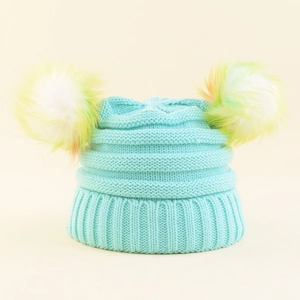 Detailed view of light blue knitted baby hat with vibrant colorful double pom-poms