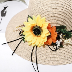 Close-up of beige woven straw hat featuring vibrant sunflower and floral decorations