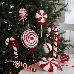 Red and white glitter candy ornaments hanging on a Christmas tree with festive lights