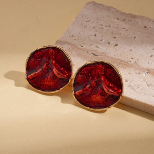 Detail shot of red drip oil earrings with gold edges and irregular lava texture surface