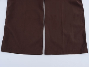 Detailed close-up of dark brown wide-leg pants hem featuring smooth pleated fabric texture