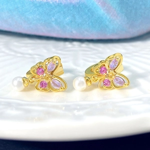 Détail macro de boucles d'oreilles papillon dorées avec zircon violet et perle