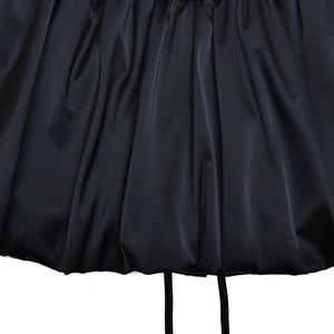 Detailed view of black satin lace-up dress showing rich fabric pleats and textures