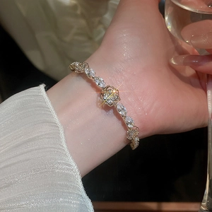 Detail of 14k gold plated flower bracelet with zircons on model's wrist with white sleeve
