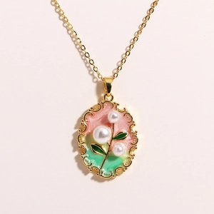 Close-up of golden oval pendant with floral enamel art and natural freshwater pearls