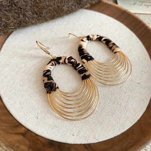 Detail of bohemian gold multi-layered drop earrings with leopard print fabric accents