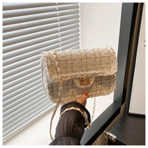 Close-up of golden beige tweed crossbody bag with metallic chain strap and twist lock