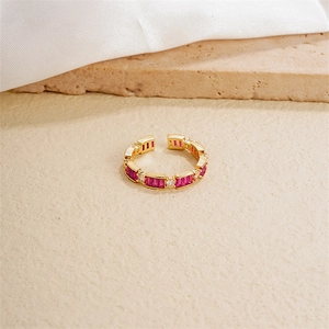 Detail of a gold adjustable ring featuring rectangular red stones and white round zircons