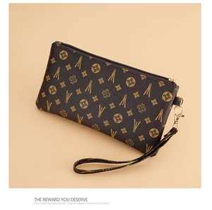 Detail of vintage brown wristlet clutch with golden geometric floral pattern and zipper