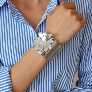 Close-up of a silver wide open cuff bracelet with a large 3D flower decorative element