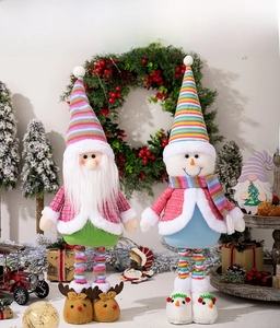 Macro detail of two plush Christmas dolls with striped hats and festive accessories