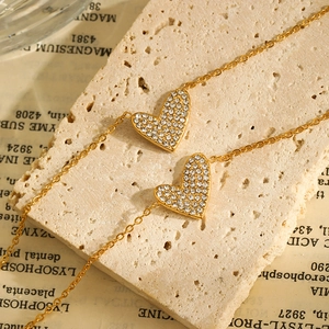 Detailed close-up of gold plated heart pendants with pavé zircons on a rustic stone base