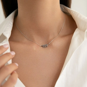Macro detail of 925 sterling silver olive leaf necklace pendant on a fine chain