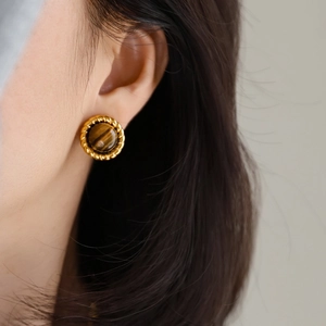 Close-up of vintage golden round stud earrings with brown tiger eye stone on model