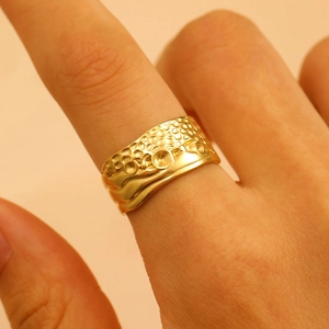 Close-up of a wide gold stainless steel ring with unique hammered bubble texture on finger
