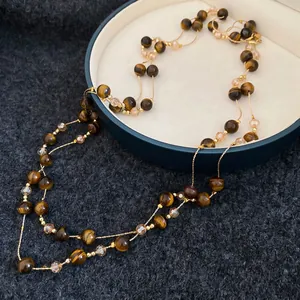 Vintage double-layer necklace with tiger eye beads and crystals on a dark jewelry box