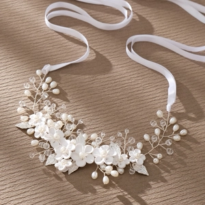 Elegant bridal hair vine with white flowers, pearls, and silver leaves on beige fabric