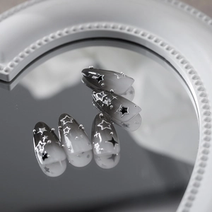 Ongles stiletto motif étoile avec dégradé noir et blanc et accents métalliques argent