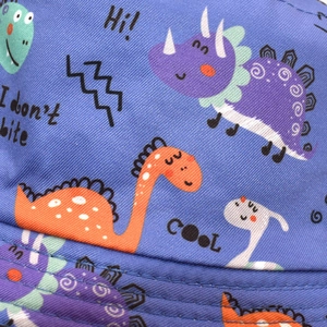 Detail of navy blue cotton fabric with cartoon dinosaur print and neat stitching