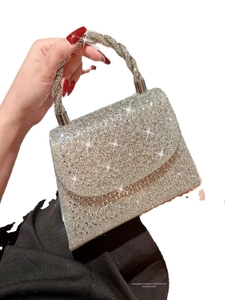 Detail of silver rhinestone handbag featuring a chunky braided handle and sparkling finish