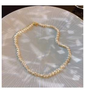 Detailed view of baroque freshwater pearl necklace on white seashell display plate
