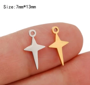 Macro shot of 7x13mm gold and silver star pendants shown on fingertip for scale
