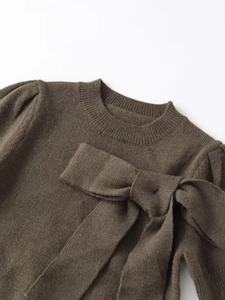 Détail d'un haut en maille marron avec un grand nœud et une texture de manches bouffantes