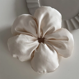 Detail of cream silk satin scrunchie featuring a large 3D flower shape and soft texture