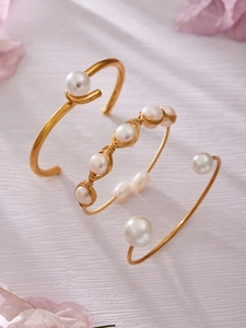 Detailed view of three gold freshwater pearl bracelets on a soft purple textured background