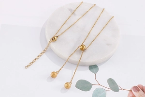 Detailed flat lay of three gold stainless steel ball necklaces on marble tray
