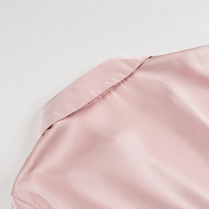 Close-up of the elegant V-neckline and silky pink satin fabric on a long sleeve dress
