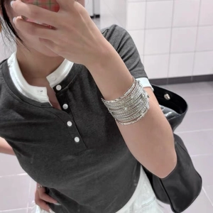 Detail of multi-layered silver cuff bracelet with textured finish on wrist