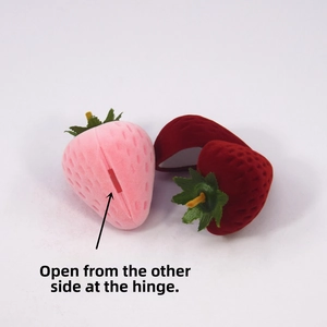 Macro detail of strawberry-shaped velvet jewelry box showing white inner lining and hinge