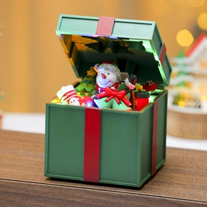 Close-up of glowing Christmas gift box with snowman, trees and colorful LED lighting