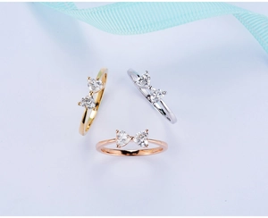 Detailed view of bow rings with heart-cut stones in gold, silver, and rose gold finishes