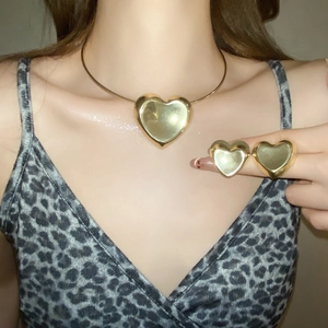 Detailed close-up of golden heart pendant necklace and matching stud earrings set
