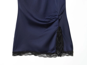 Dettaglio di un abito in raso blu navy con pizzo nero delicato e spacco laterale raffinato