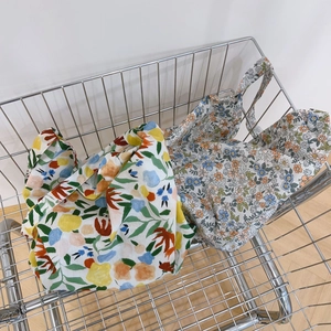 Close-up of floral cotton tote bags in a metal cart with vintage and aesthetic prints