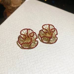 Macro shot of vintage gold flower earrings with deep red enamel and intricate woven texture