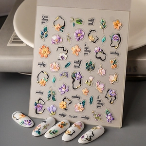 Close-up of 3D embossed floral nail stickers with gold outlines and purple flower designs