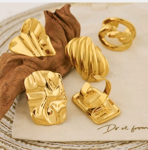 Detailed view of gold 18k irregular pleated rings on rustic fabric and wood background