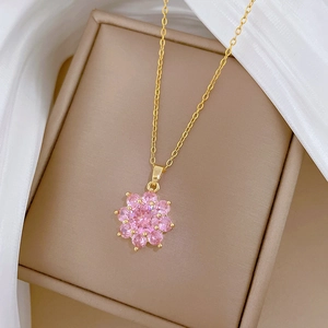 Detail of a gold floral necklace with pink stones resting on silk inside a jewelry box