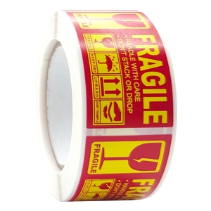 Macro shot of red Fragile warning labels on a roll with international shipping icons