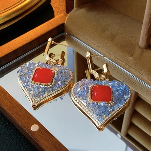 Macro shot of vintage heart drop earrings with red square crystal and blue accents