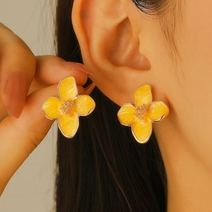 Elegant yellow four-petal flower earrings with gold metal trim worn by a model