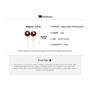 Macro shot of long red pompom earrings with pearl flowers and white beaded tassels