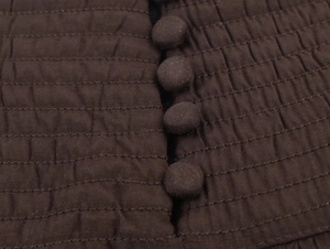 Détail d'une robe midi marron foncé avec tissu froncé et boutons recouverts