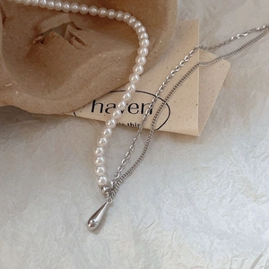 Macro view of teardrop pendant with silver metal chain and white faux pearls